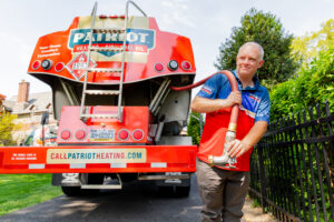 Driver holding the delivery hose at the rear of the heating oil tanker