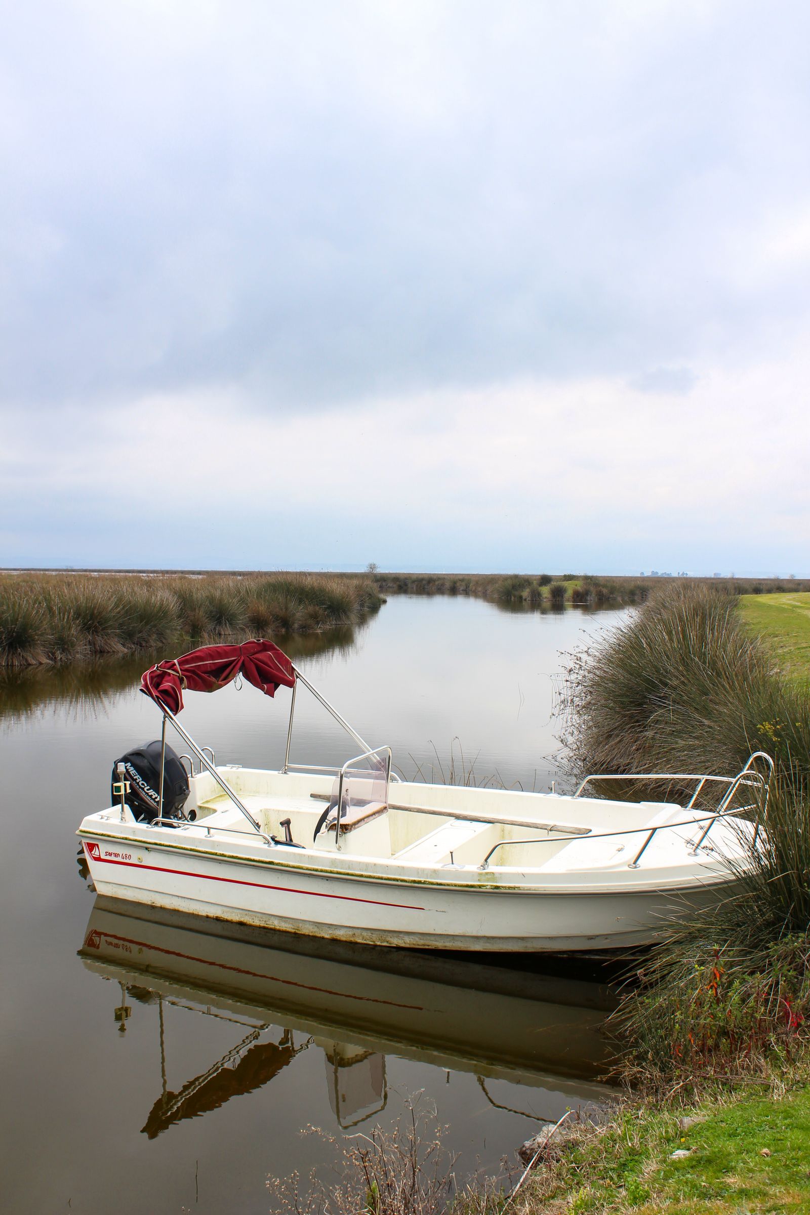 A center-console skiff moored against marsh grass on a New Jersey back bay