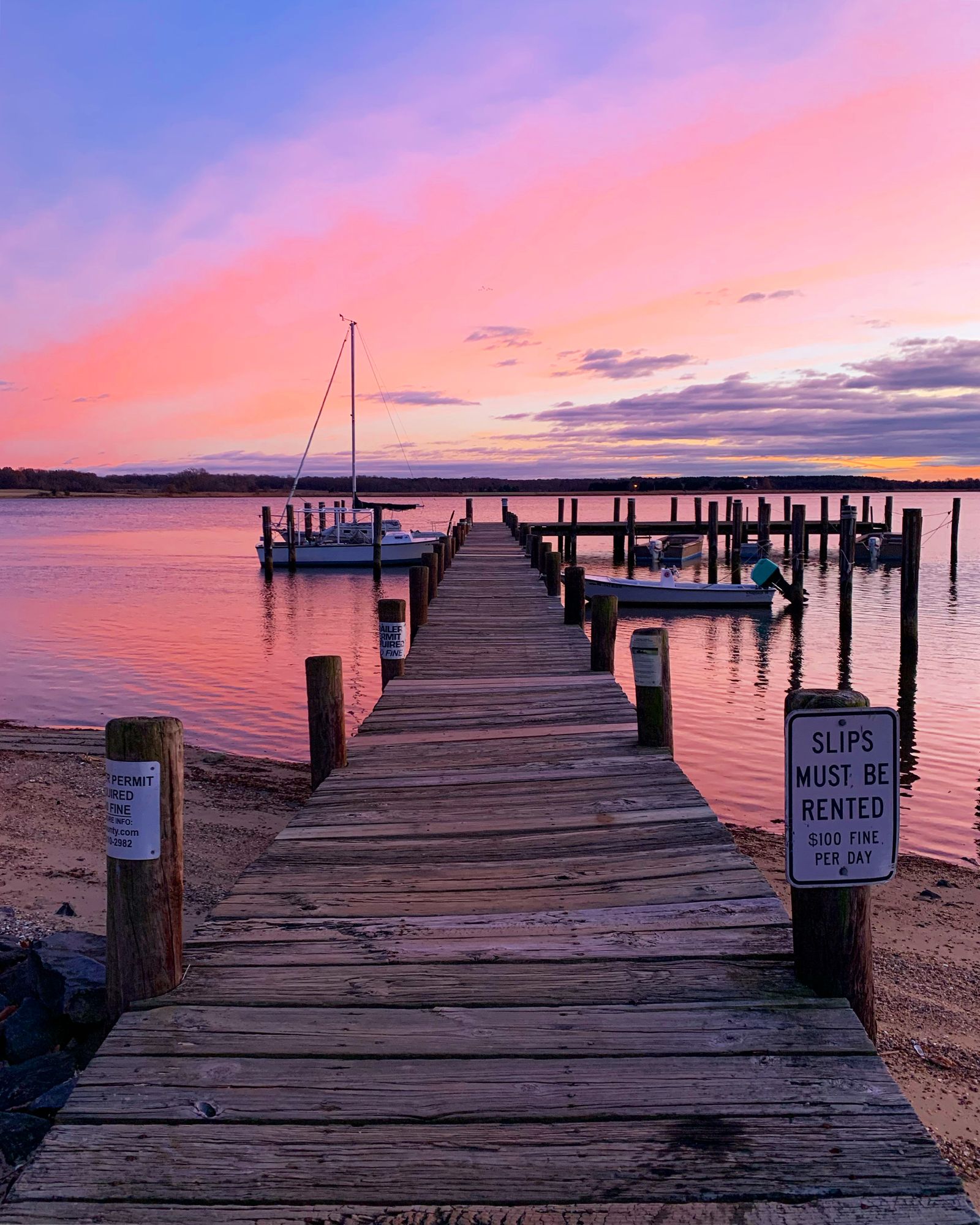 A wooden dock and moored boats at sunset on a quiet bay, where marine diesel is delivered in Port Republic, NJ