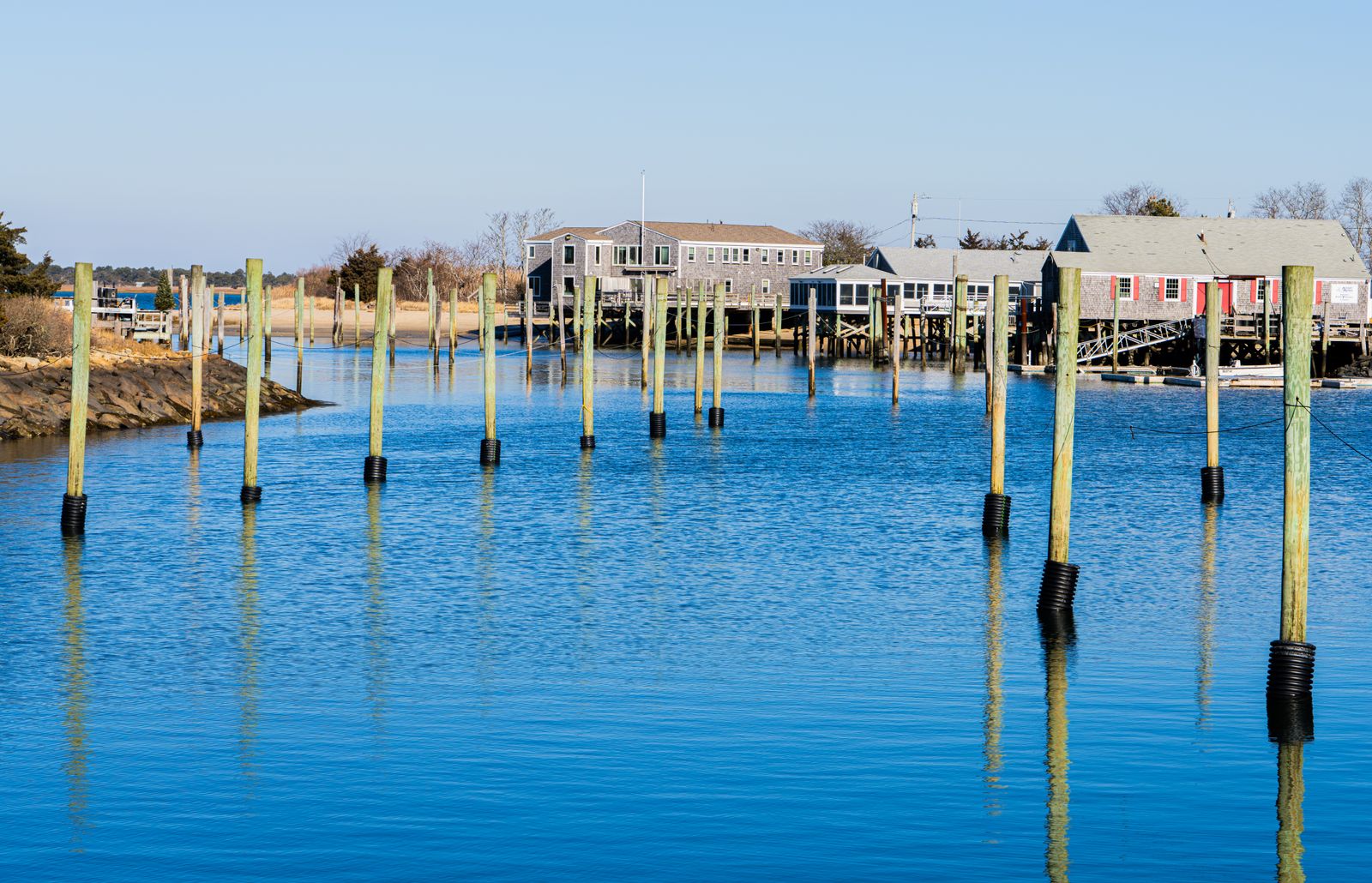 Boats and shingled dock buildings on a Northeast river harbor, where marine diesel is delivered in Manasquan, NJ